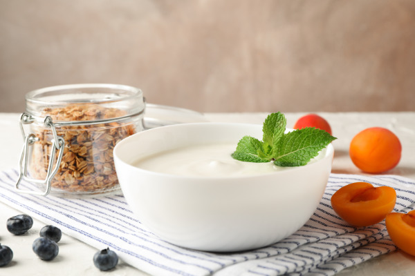 Composition with granola, yogurt and fresh fruits on white cement background